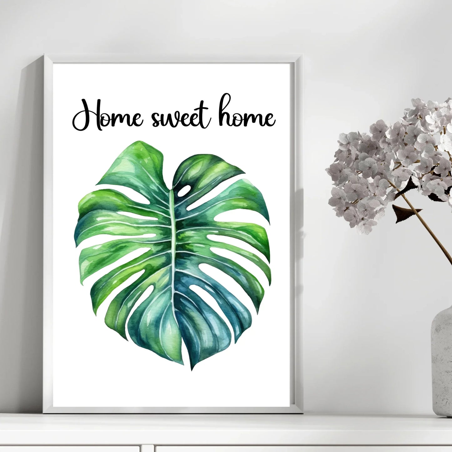 Home decor poster with Monstera leaf illustration and 'Home sweet home' text, beside vase of flowers