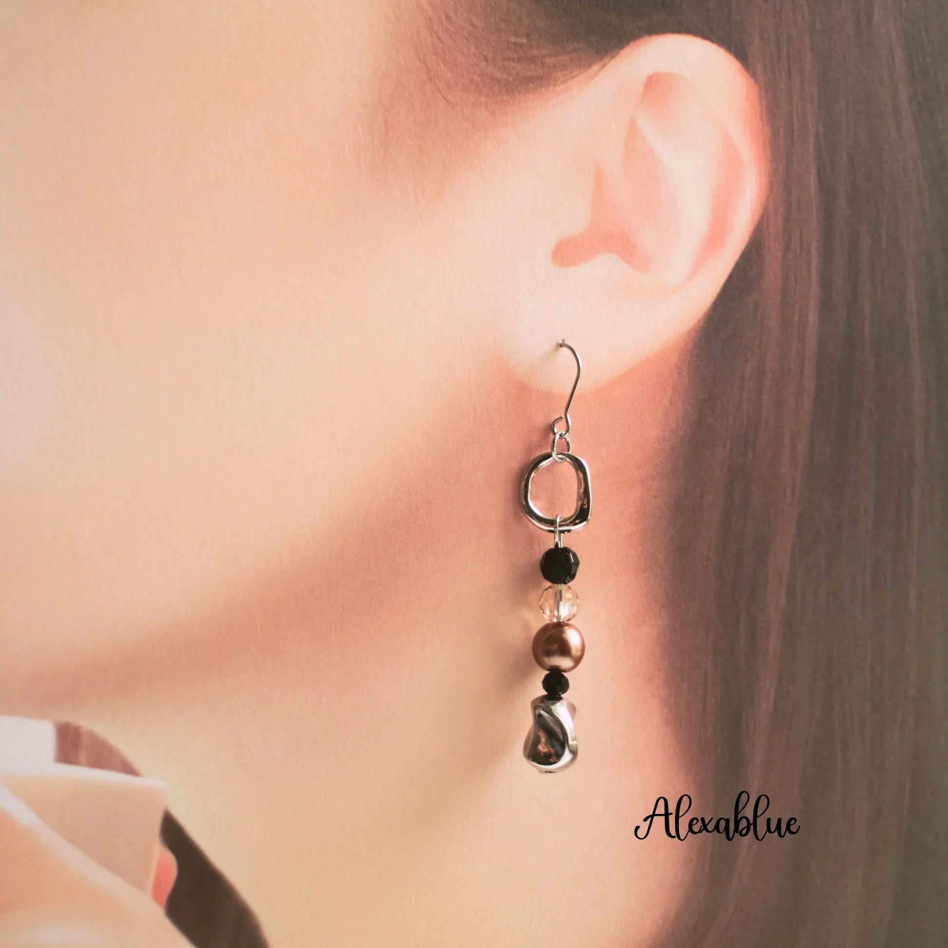 Natural stone dangle earring with gold and black beads worn on ear, elegant accessory