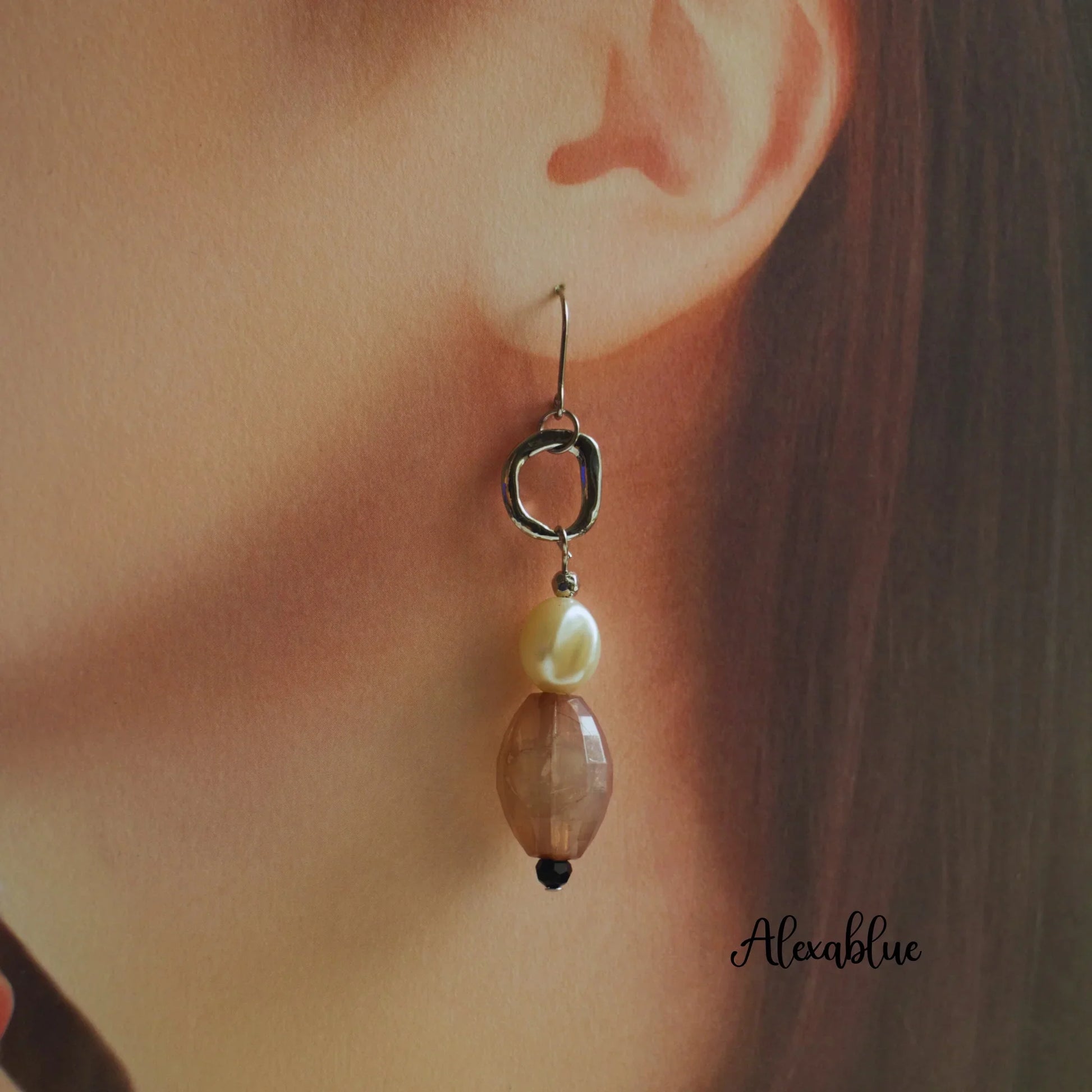 Dangling natural stone earring with pearl bead on a woman's ear, elegant jewelry