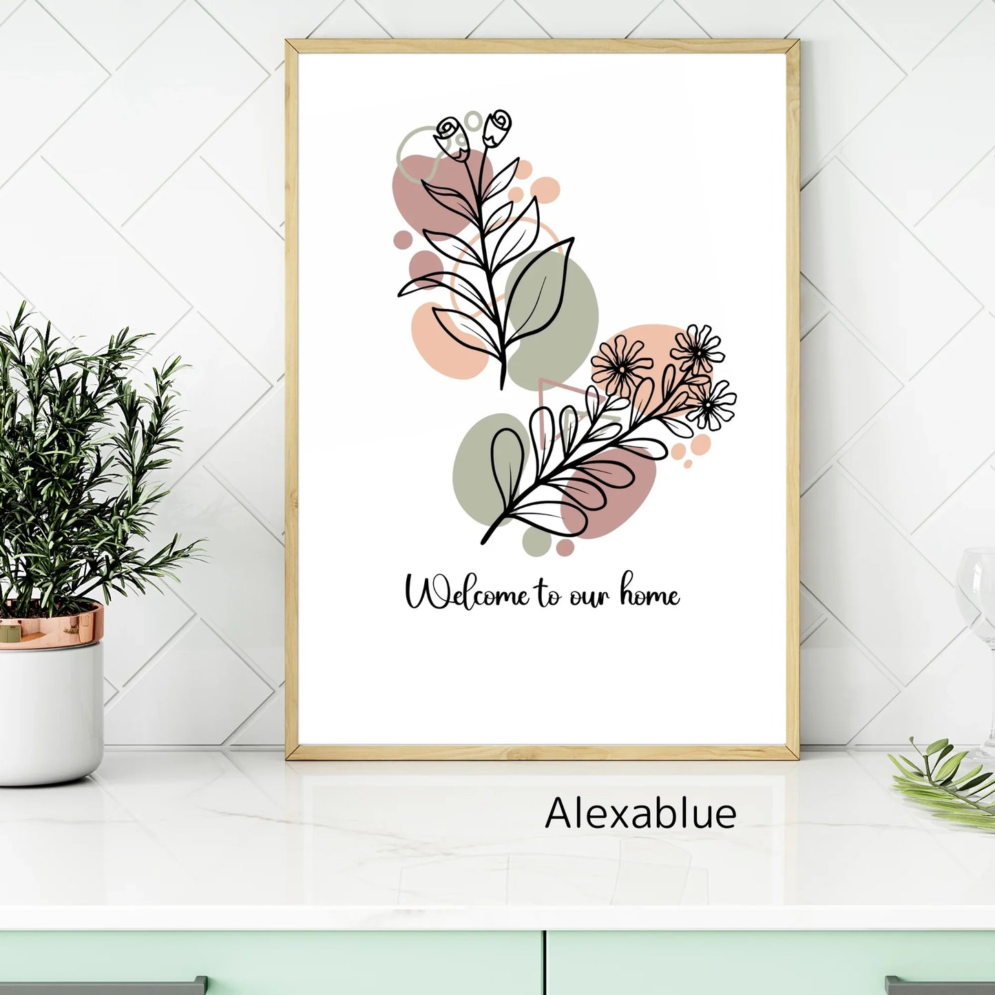 Framed botanical wall art with line drawing flowers and text 'Welcome to our home' on a modern kitchen counter.