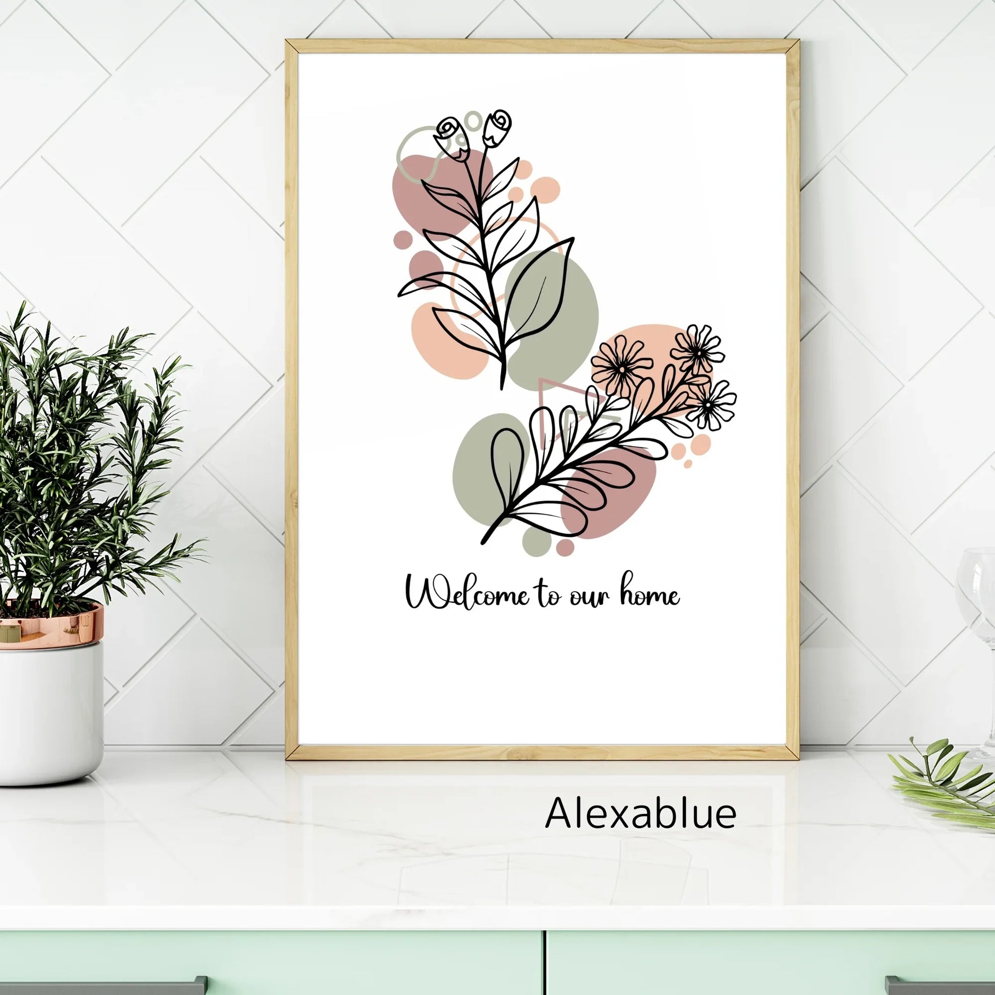 Framed botanical wall art with line drawing flowers and text 'Welcome to our home' on a modern kitchen counter.