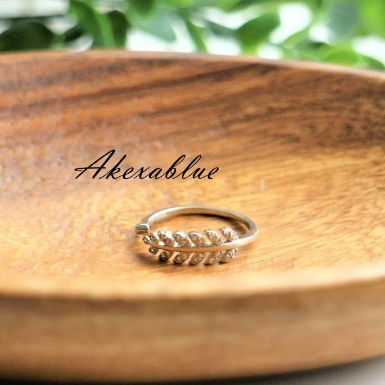 silver leaf motif natural stone ring on wooden dish with greenery in background