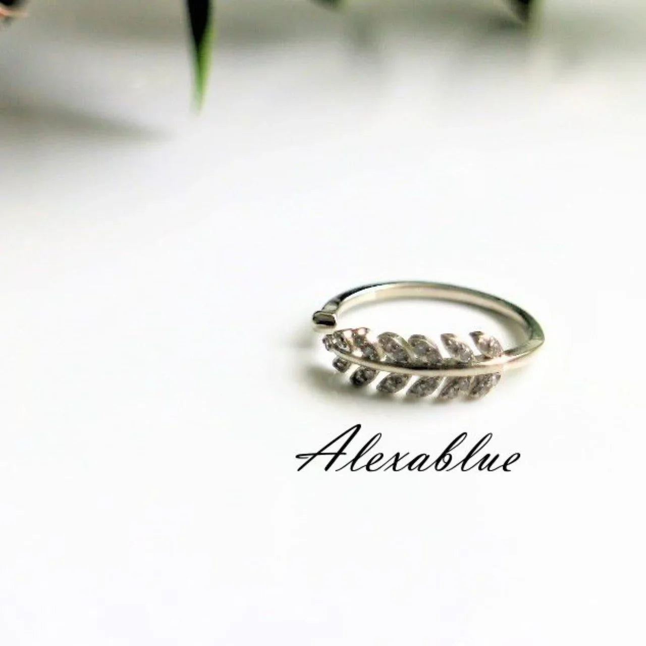 Silver leaf-shaped adjustable ring on white background, minimalist jewelry design
