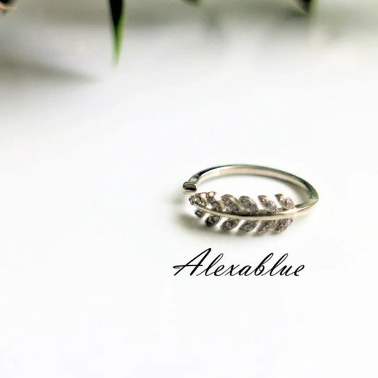Silver leaf-shaped adjustable ring on white background, minimalist jewelry design