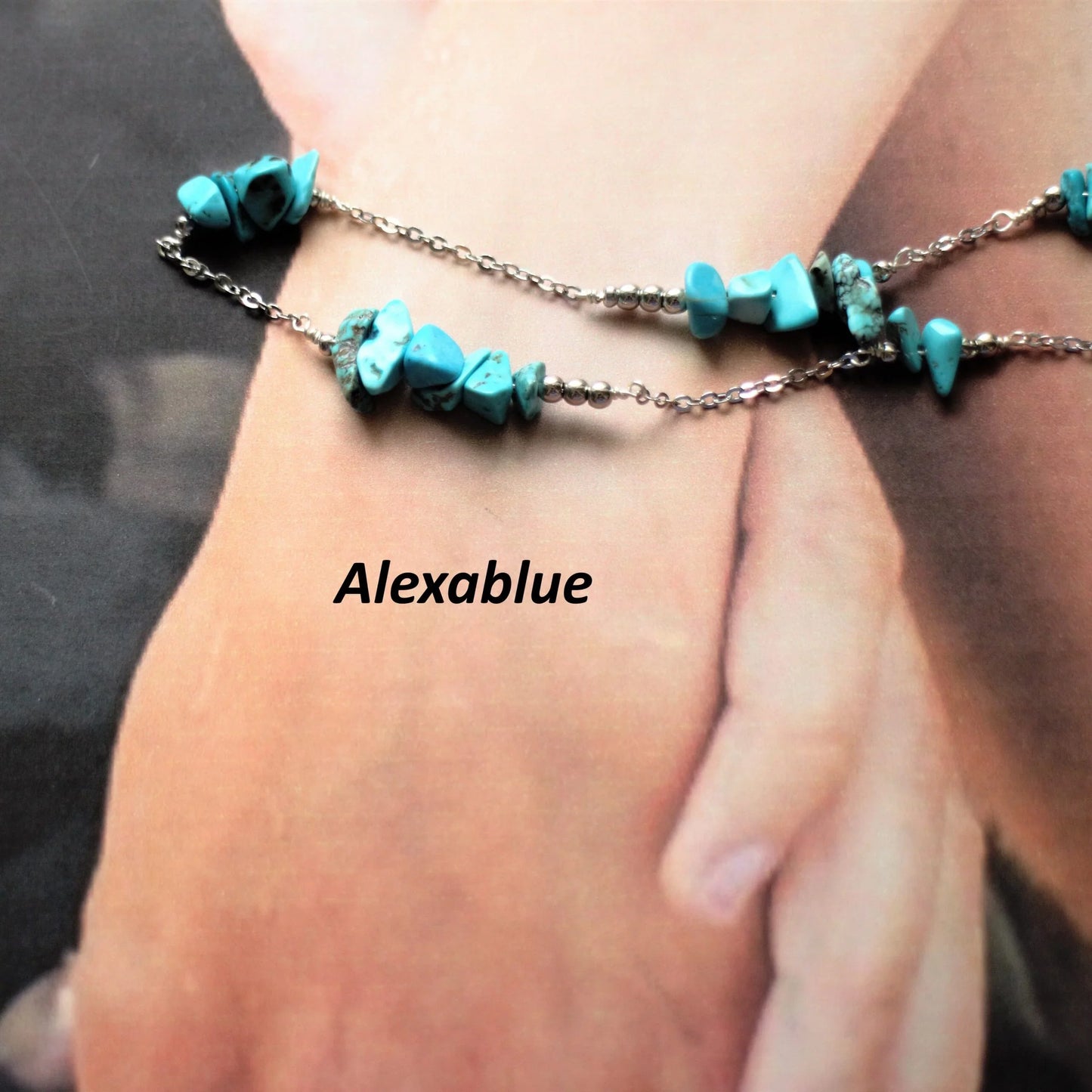 Turquoise natural stone beaded necklace with silver chain on soft hands background