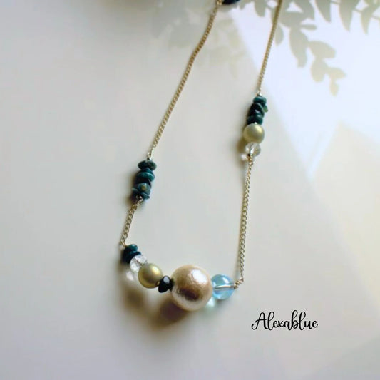 Gold chain necklace with natural stones, pearls, and crystal beads on a white background.