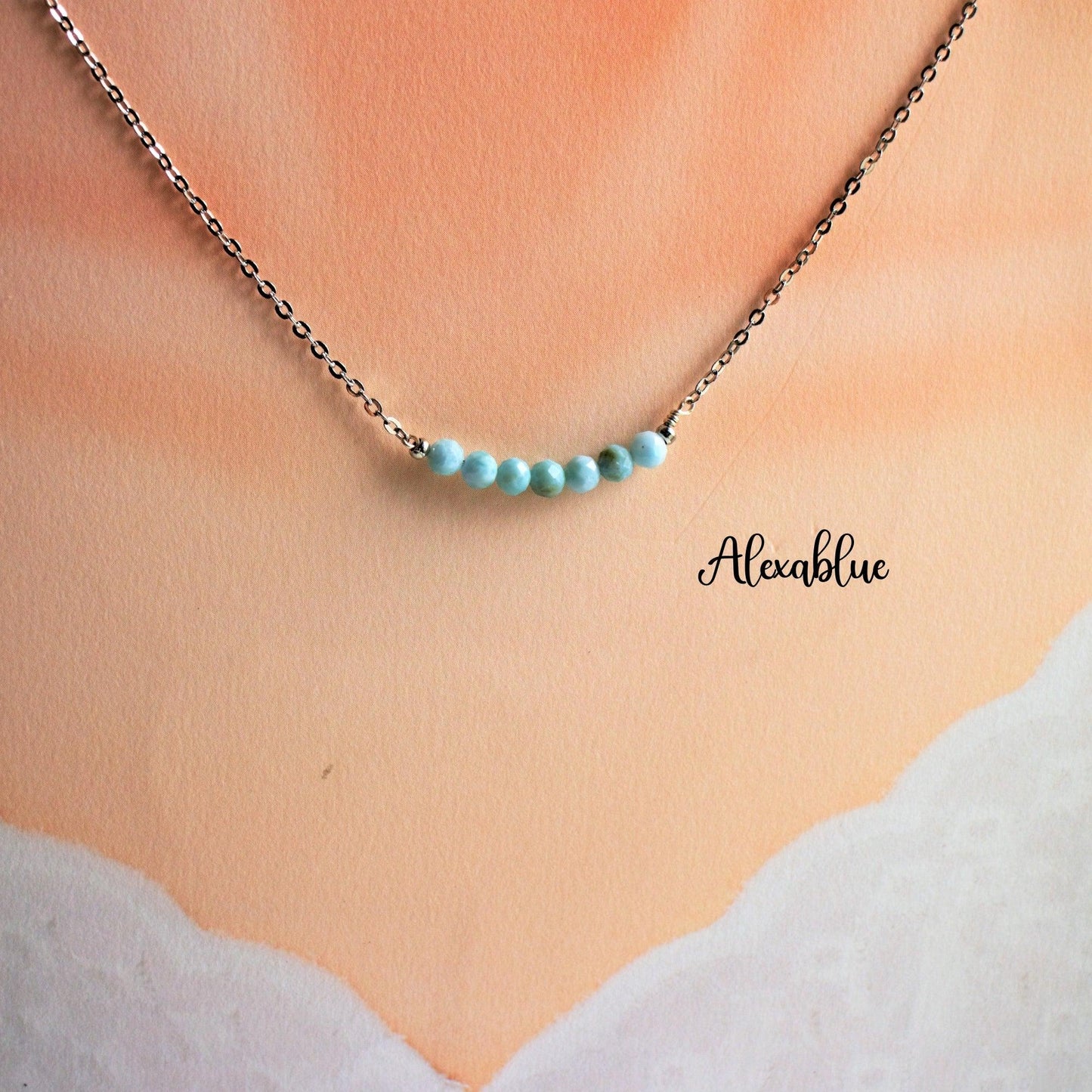 Delicate silver chain necklace with small blue natural stone beads displayed on a soft background.