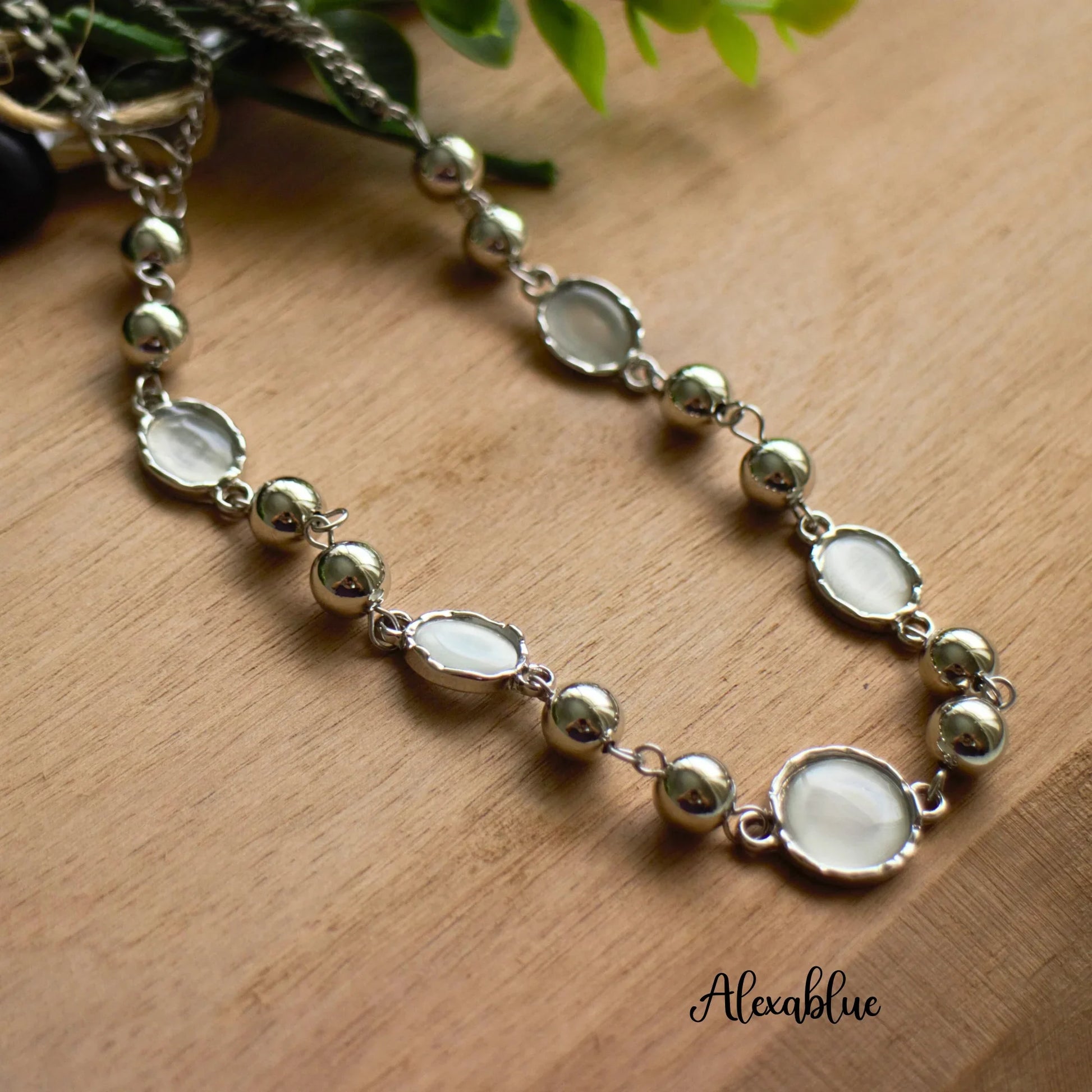 Silver natural stone necklace with round beads and white gemstones on wood background