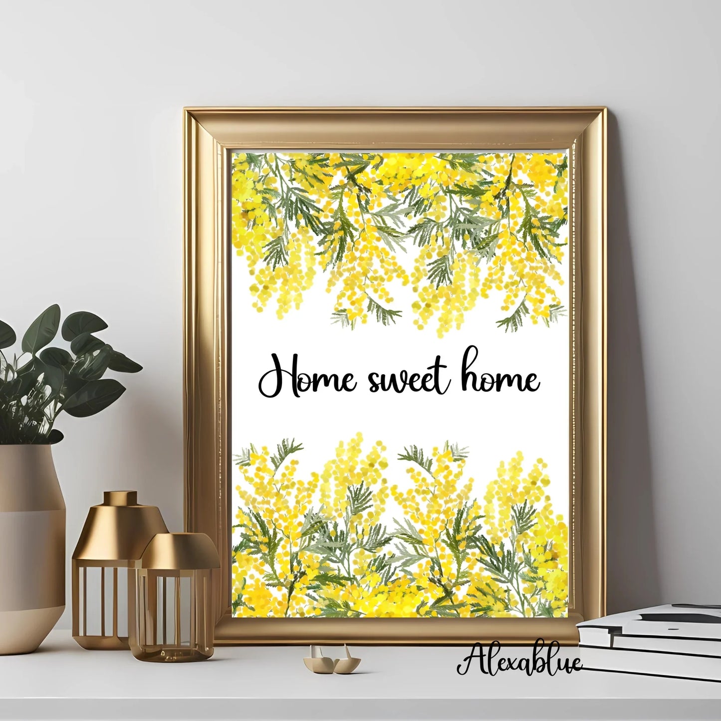 Gold framed floral wall art print with 'Home sweet home' text, displayed on a modern shelf with golden candle holders, plants, and decor books.