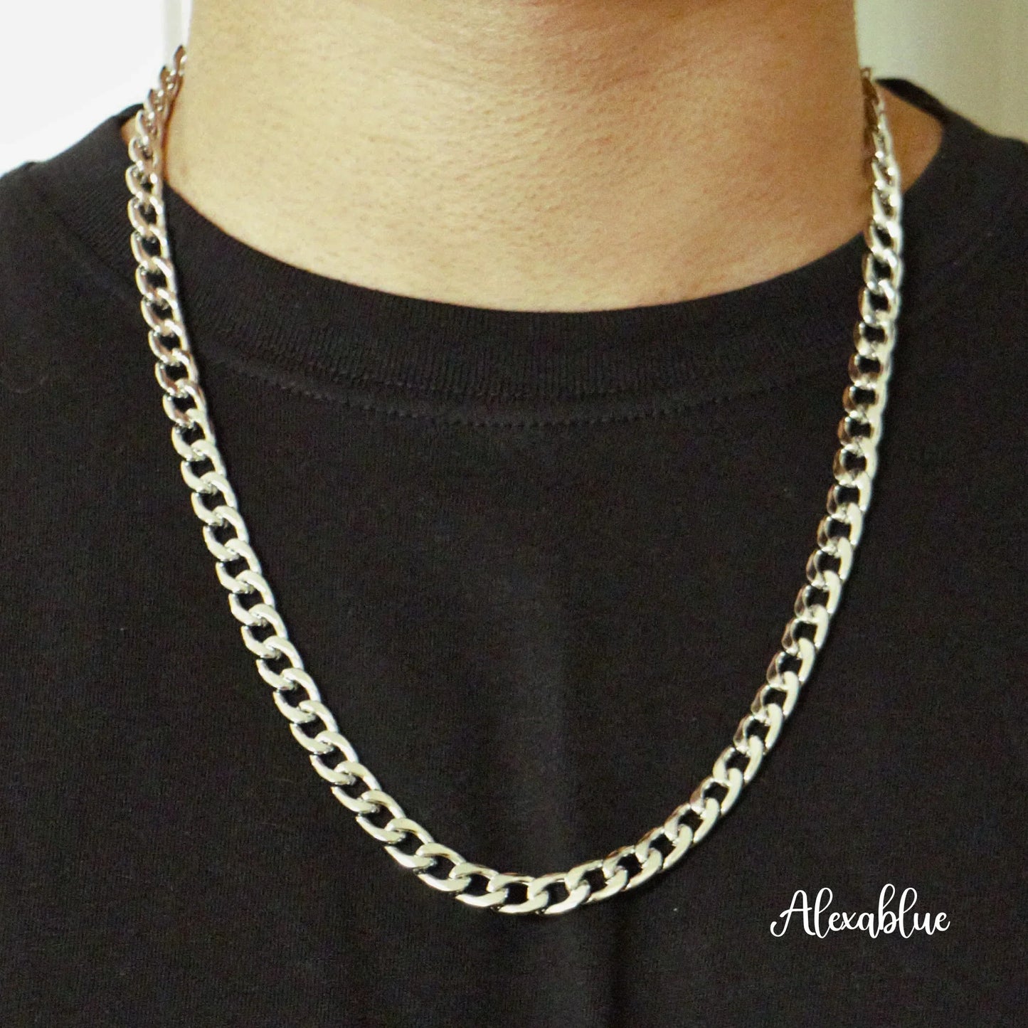 Close-up of a silver chain necklace with curb links worn over a black shirt