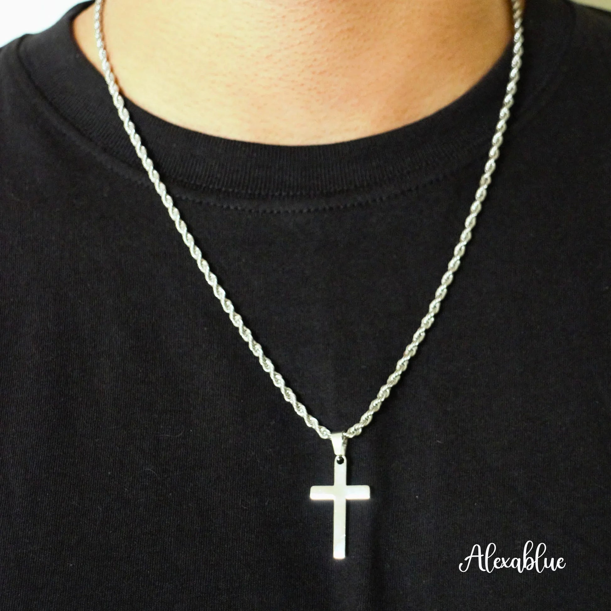 Silver cross necklace with rope chain on person wearing black shirt, minimalist jewelry style