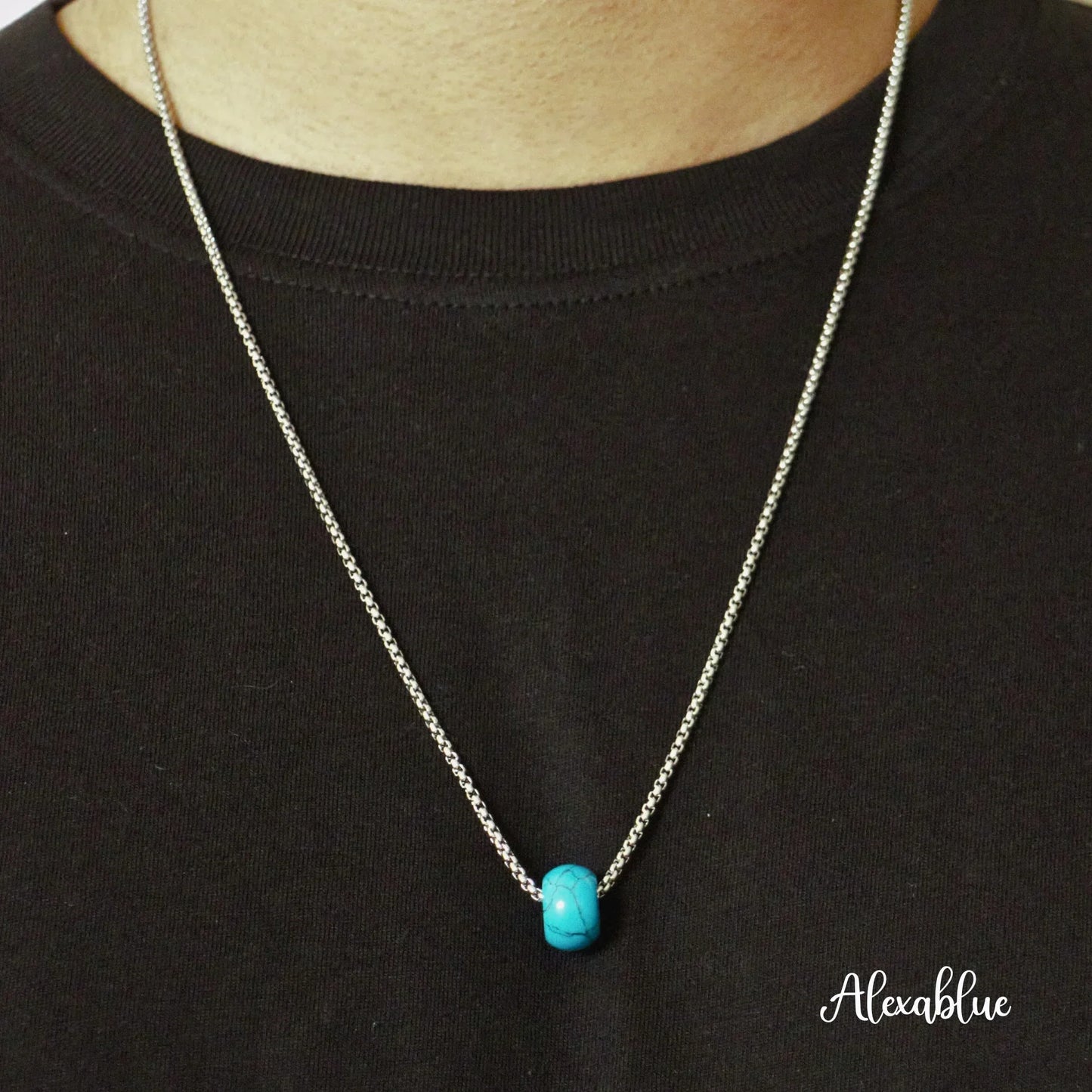 Silver chain necklace with a turquoise natural stone bead pendant on a black shirt