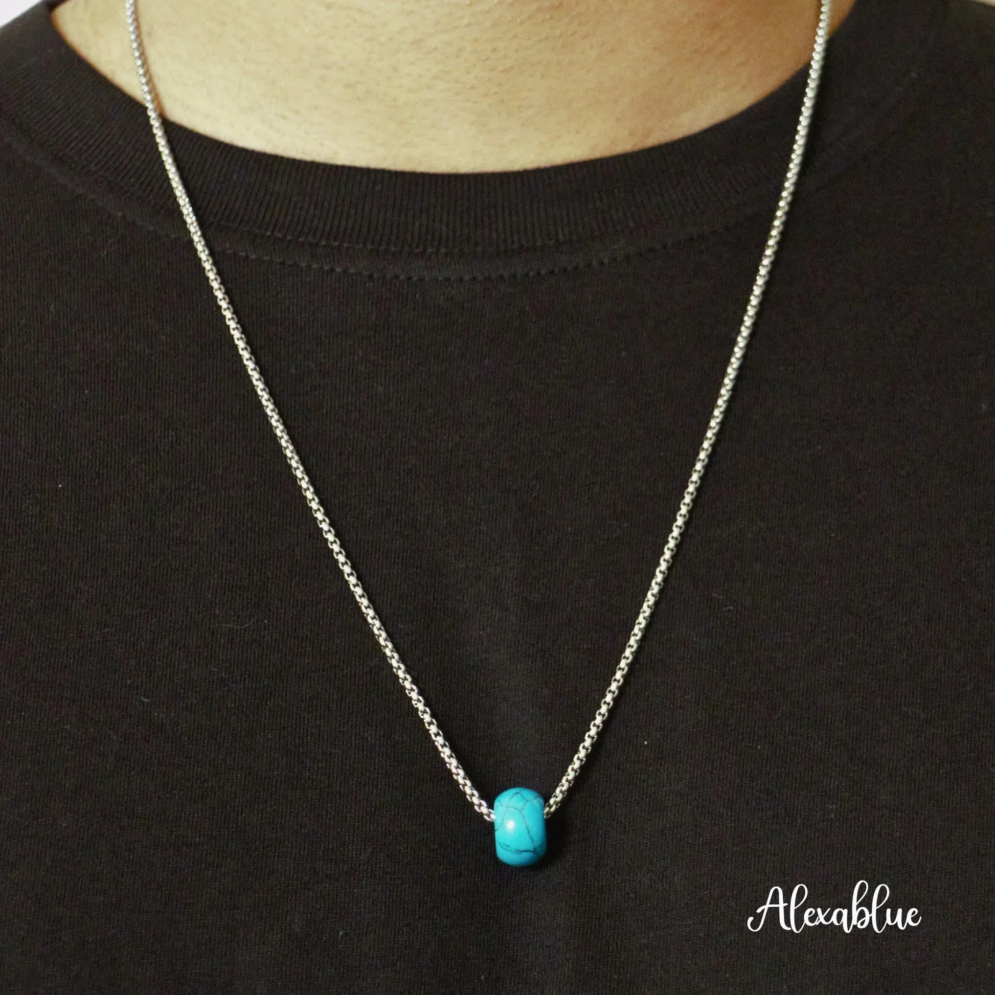 Silver chain necklace with a turquoise natural stone bead pendant on a black shirt