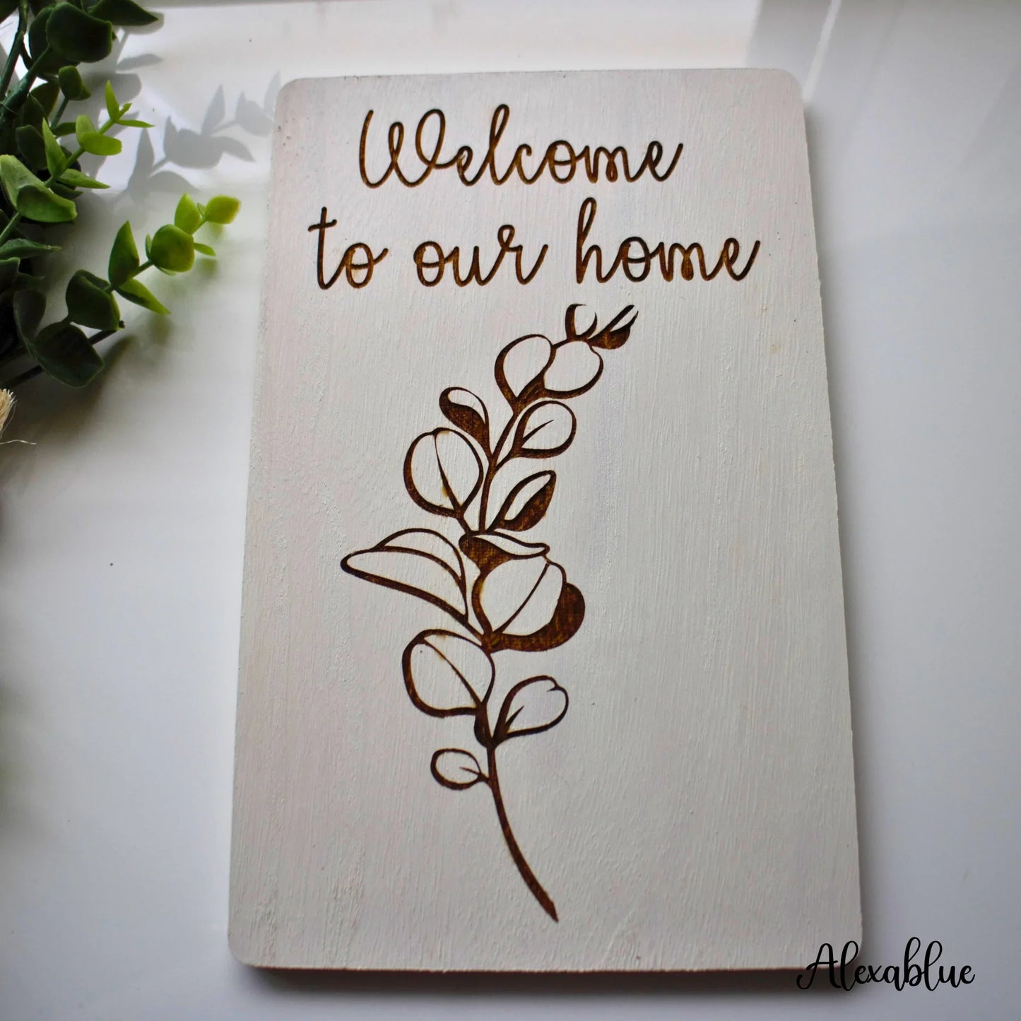 Wooden welcome sign with floral engraving and 'Welcome to our home' text, home decor